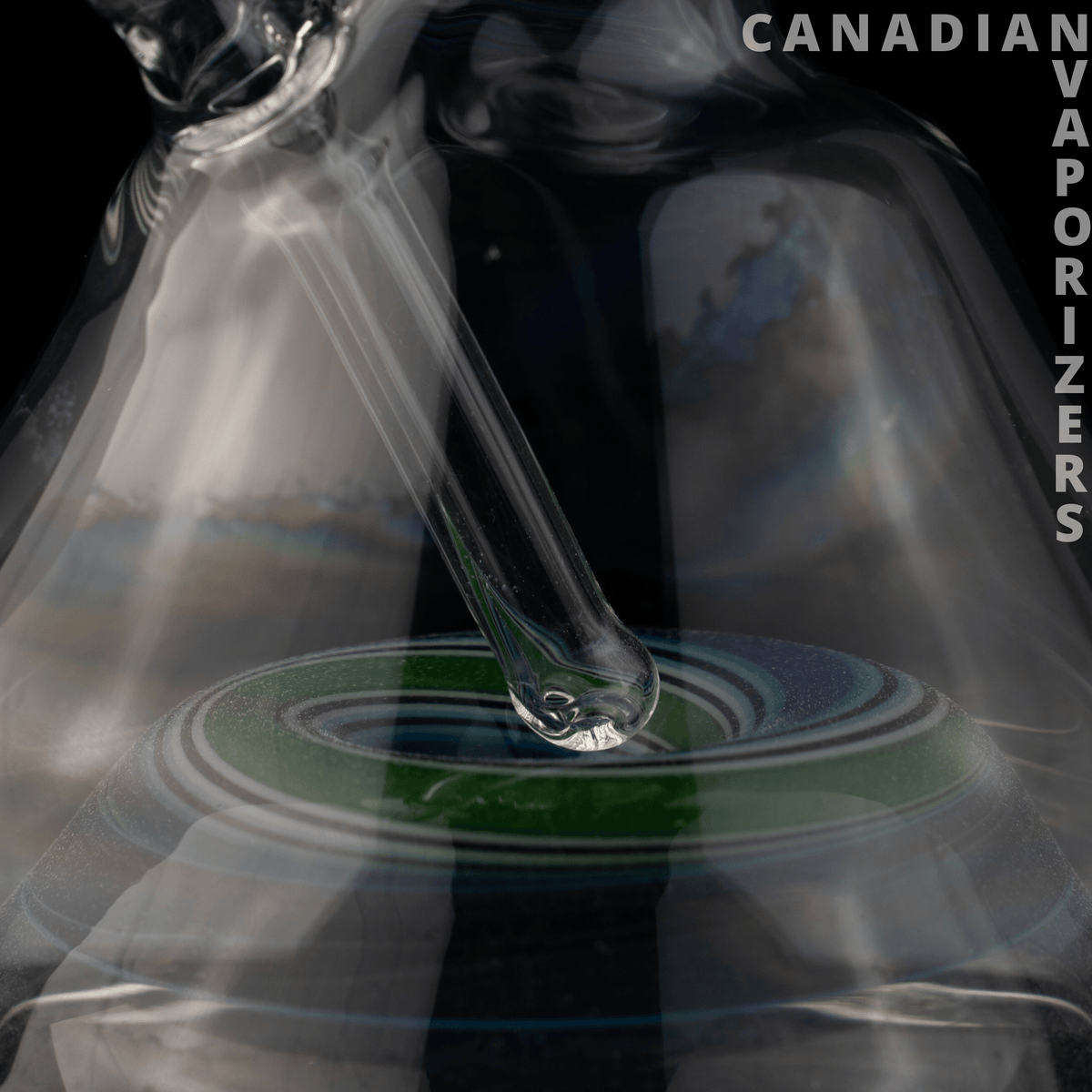 Barracuda Glass - Clear glass pipe stem rests over a dark circular surface with green and blue concentric rings.